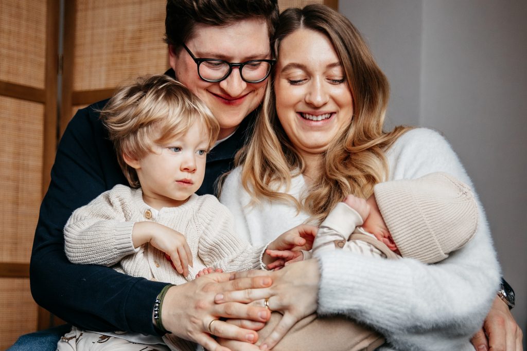Familie sitzt gemeinsam auf dem Foto und schaut Baby an